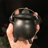6Witch3 Mini Cast Iron Painted Cauldron - a small round black cauldron is held in the palm of a hand, it looks vaguely threatening like a witchy grenade.