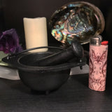6Witch3 Cast Iron Cauldron with Pestle - The pestle is shown inside the cauldron and both are shown next to a pink lighter for scale.