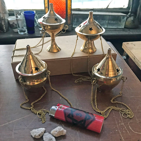 6Witch3 small brass incense burners - group shot on a brown box next to a lighter and some resin incense