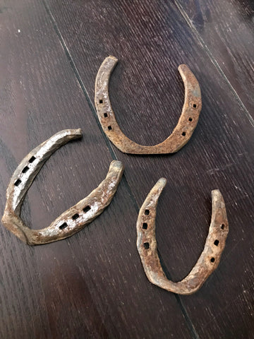 6Witch3 Used Horseshoes, three horseshoes of assorted size, rusted and slightly uneven, resting on a dark brown wood background