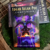 6Witch3 Edgar Allan Poe Tarot - the front of the box with the Edgar Allan Poe Companion guidebook leaning against it, shown on a circle of green moss resting on a wood background