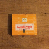 6Witch3 Sandalwood Incense Cones by Satya -A single yellow box of cones rests on a wood background